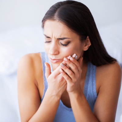 Woman holding her jaw in pain, representing orthodontic pain relief
